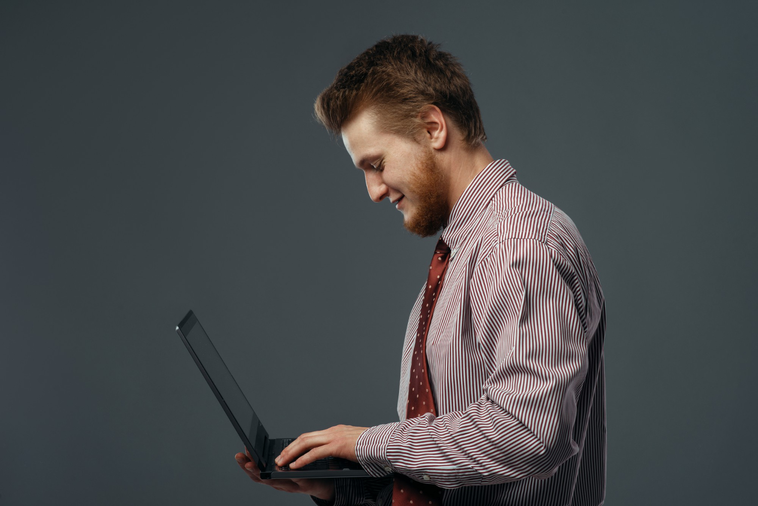 A guy is standing with a laptop in his hands and working
